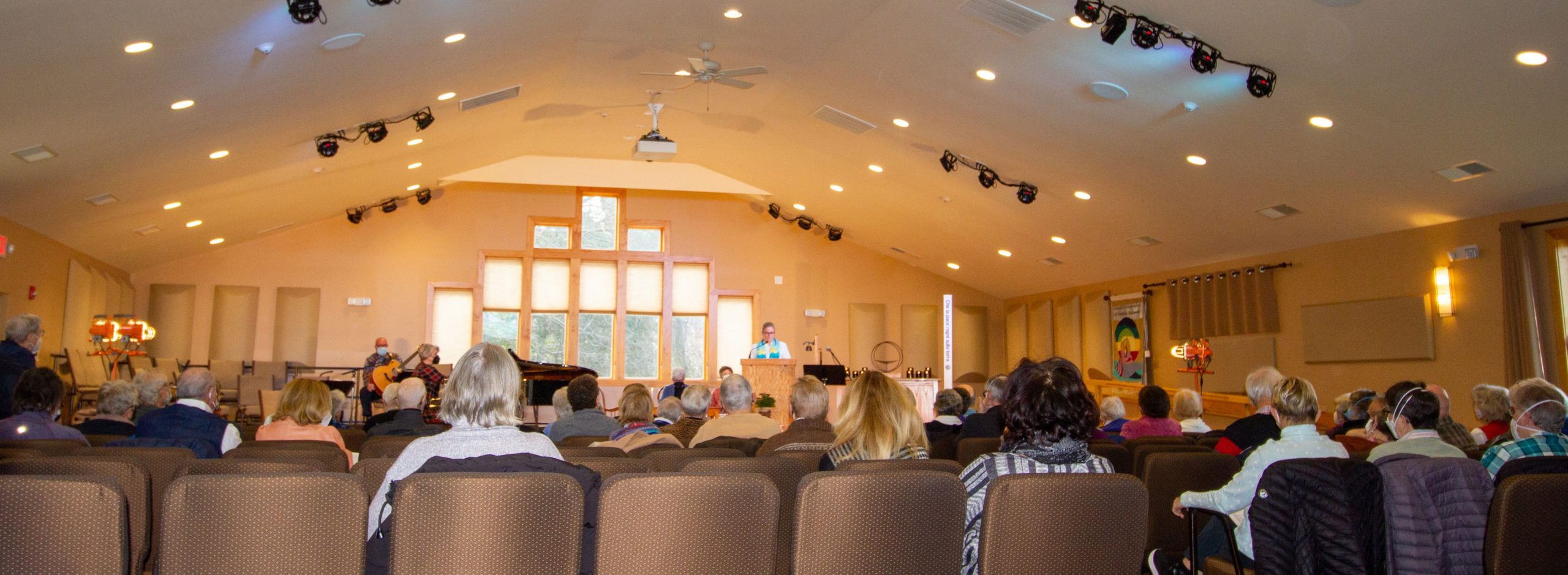 The UUSD congregation seen from the back of the sanctuary with rev. heather in the pulpit