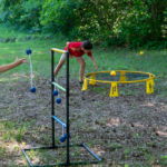 A girl playing ladder toss and two boy playing Spikeball