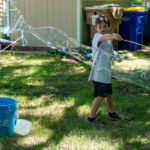 Two boys making giant bubbles with wands