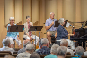 Three people with microphones and Julie at the piano.