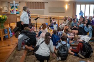 The children & youth gather at the front of the sanctuary for the backpack blessing.